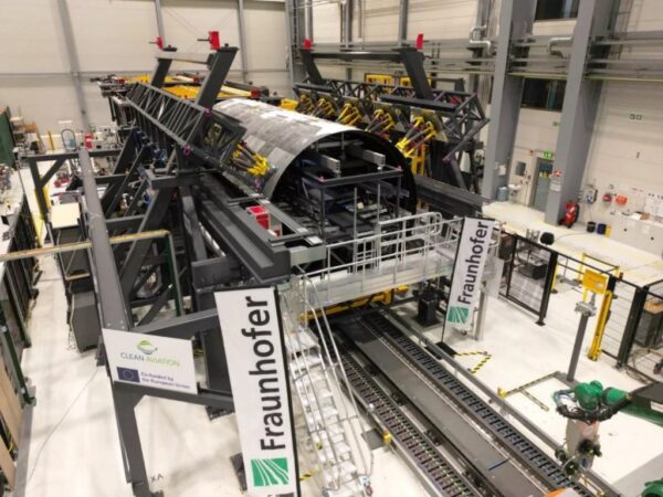 Fraunhofer IFAM使用黃色六足機器人固定熱塑性機身殼體MFFD在組裝平台上並進行高精度殼體形狀調整和雷射銲接。Fraunhofer IFAM/提供 「航空材料的創新,環保熱塑性機身」